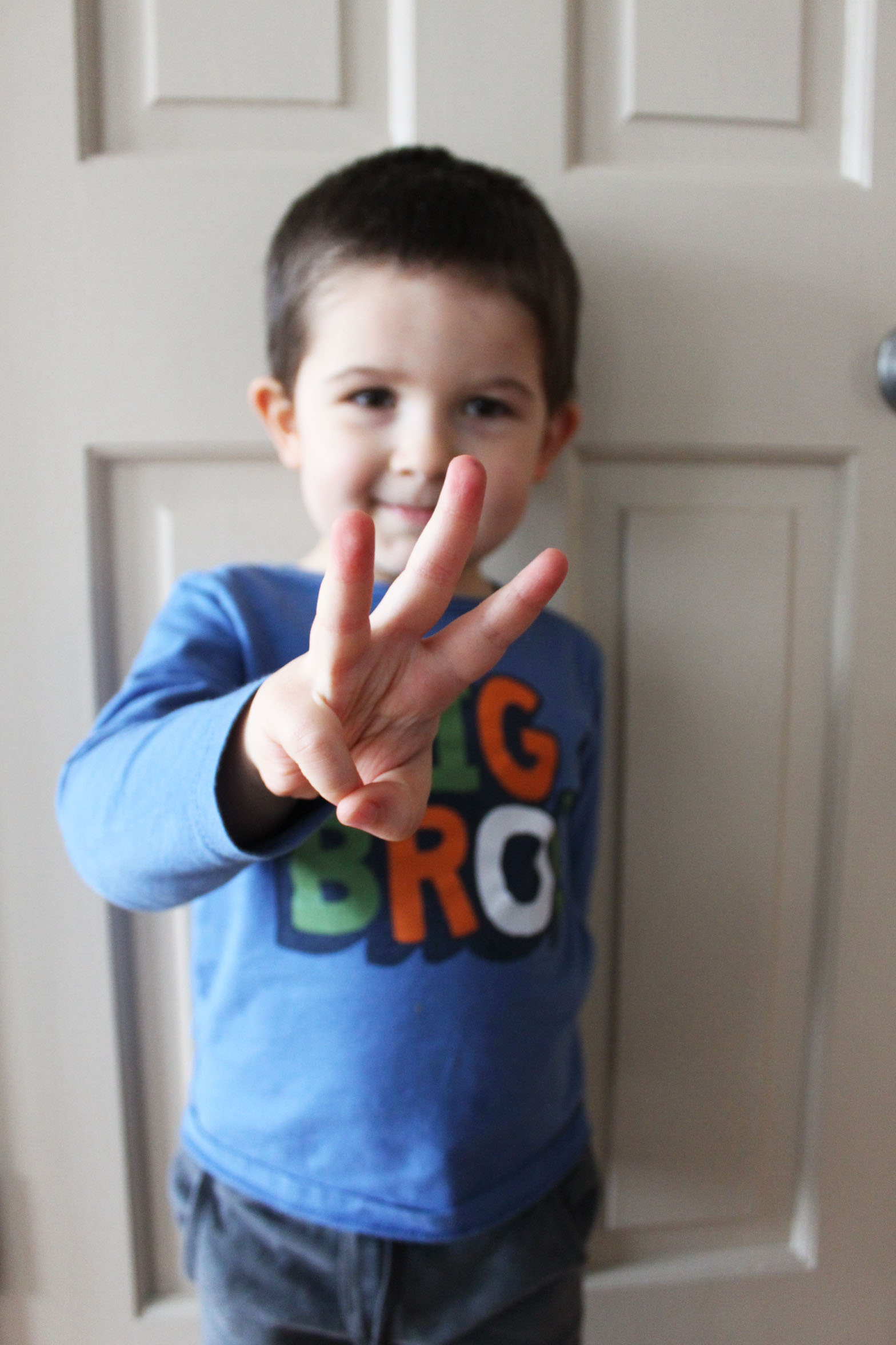 young boy holding up three fingers