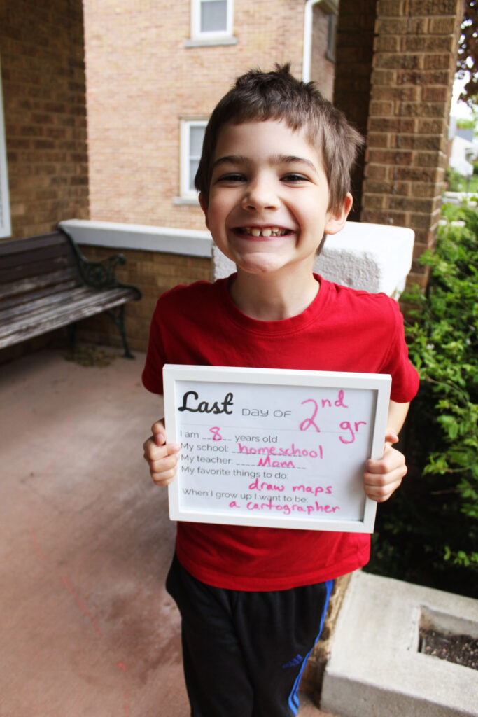 second grade boy holding homeschool year sign