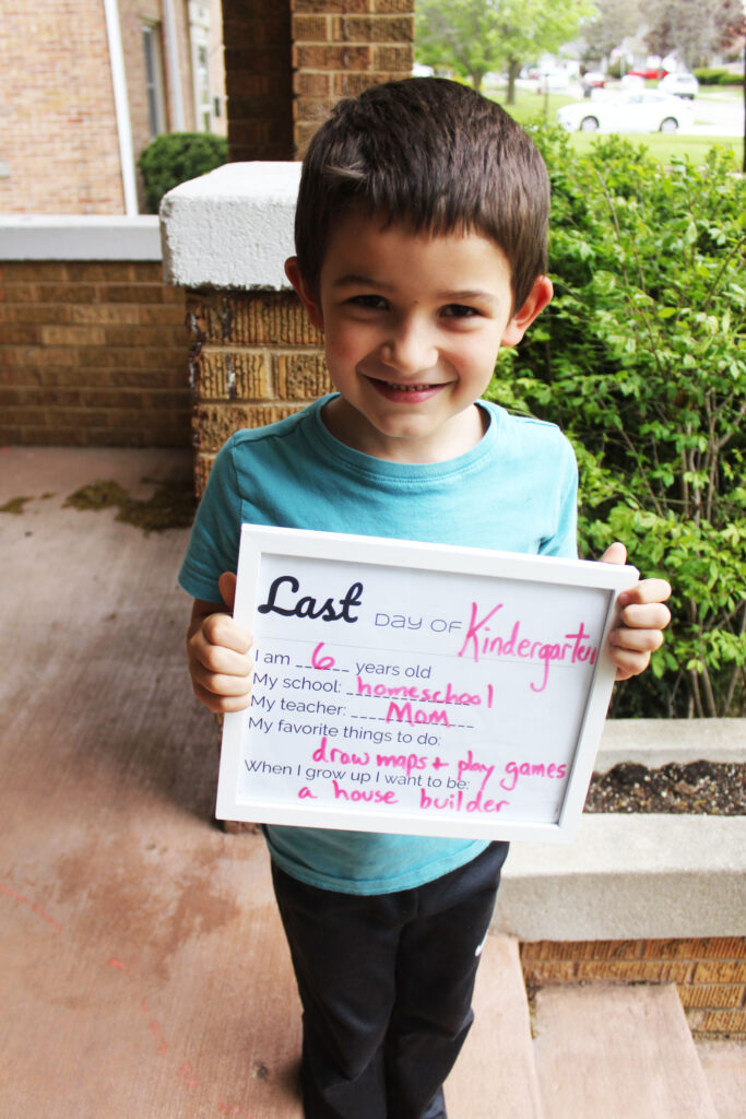 kindergarten boy holding homeschool year sign