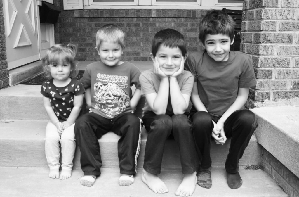 four homeschool children sitting on porch