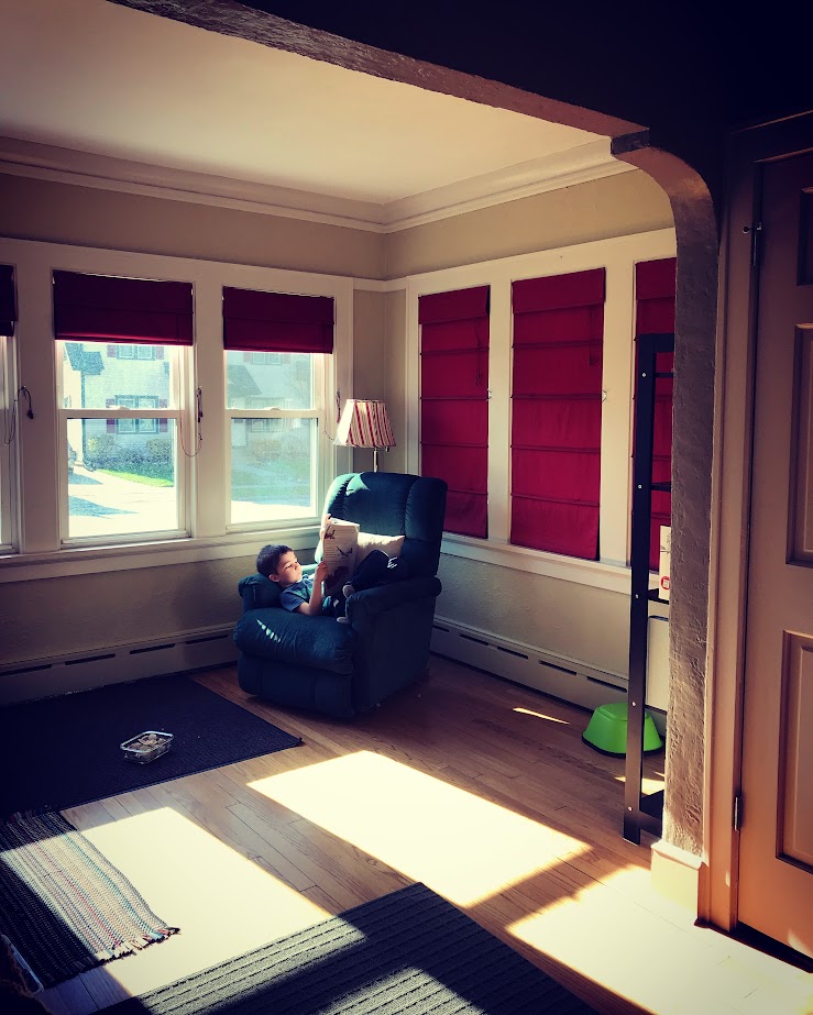 young boy reading alone in a chair in the corner