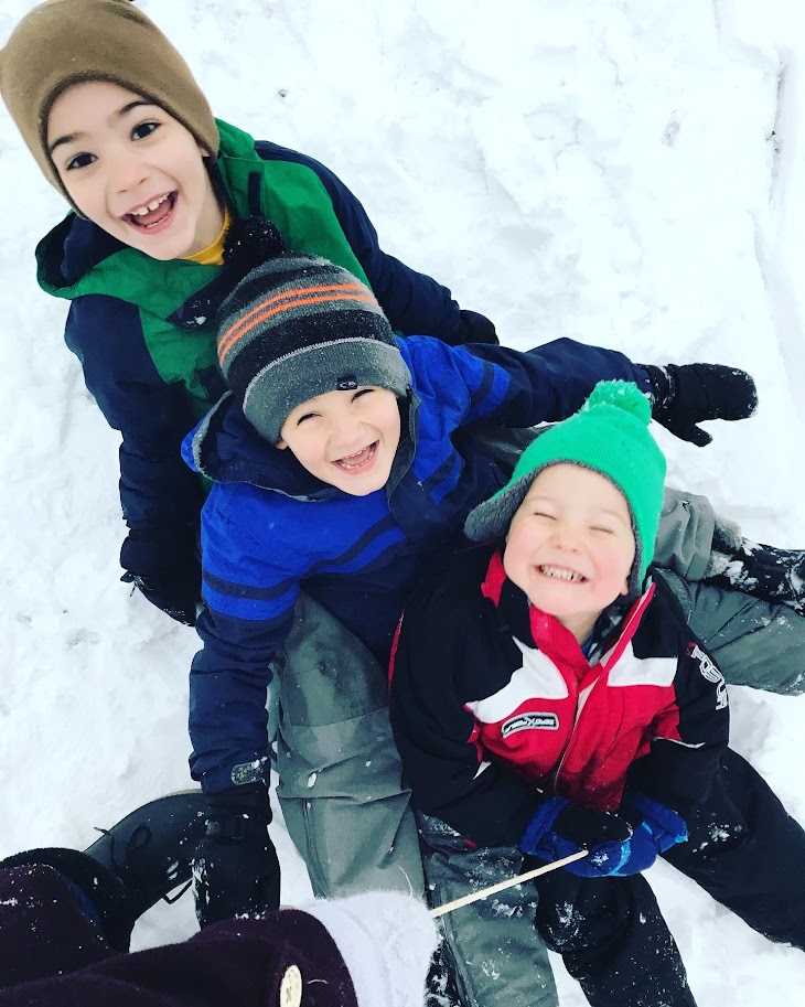 three homeschool boys on a sled in the snow