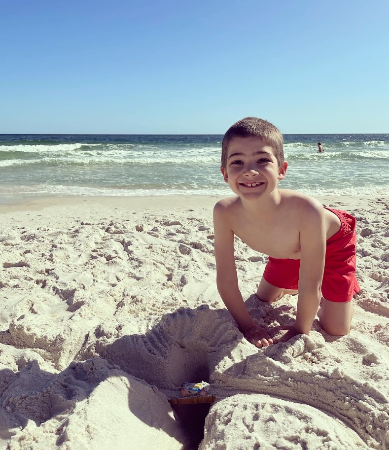 homeschool boy digging in sand at the beach