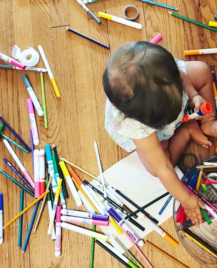 baby girl dumping pencils on the floor