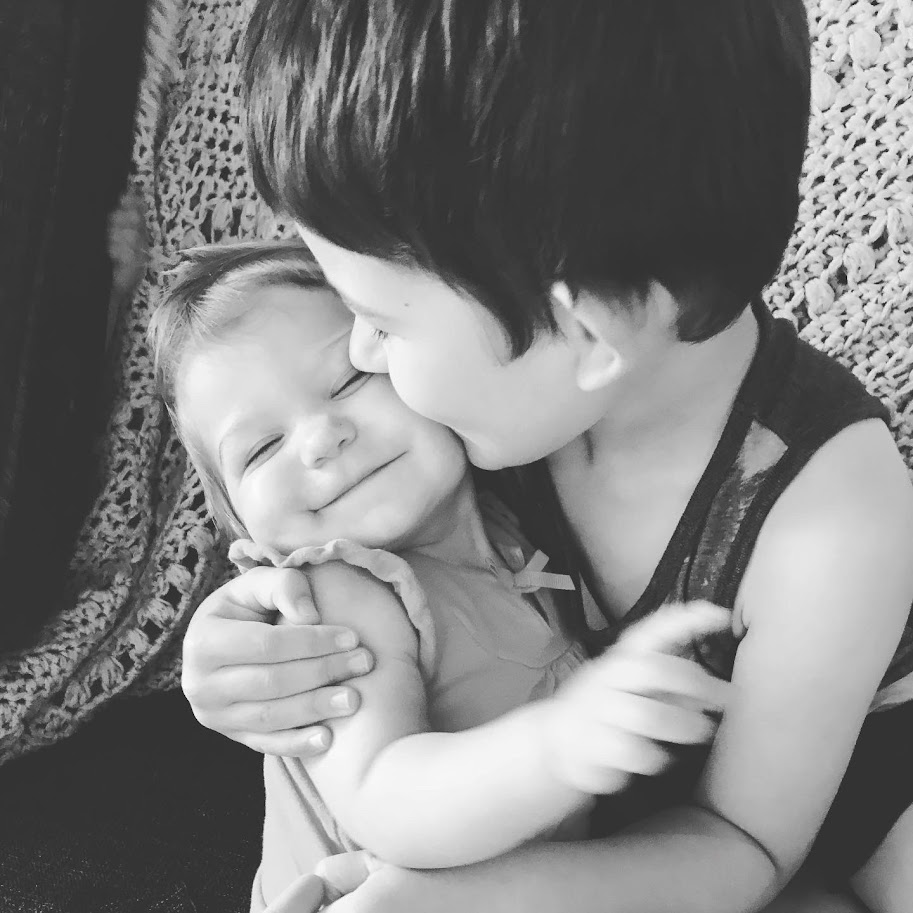 young boy kissing baby sister