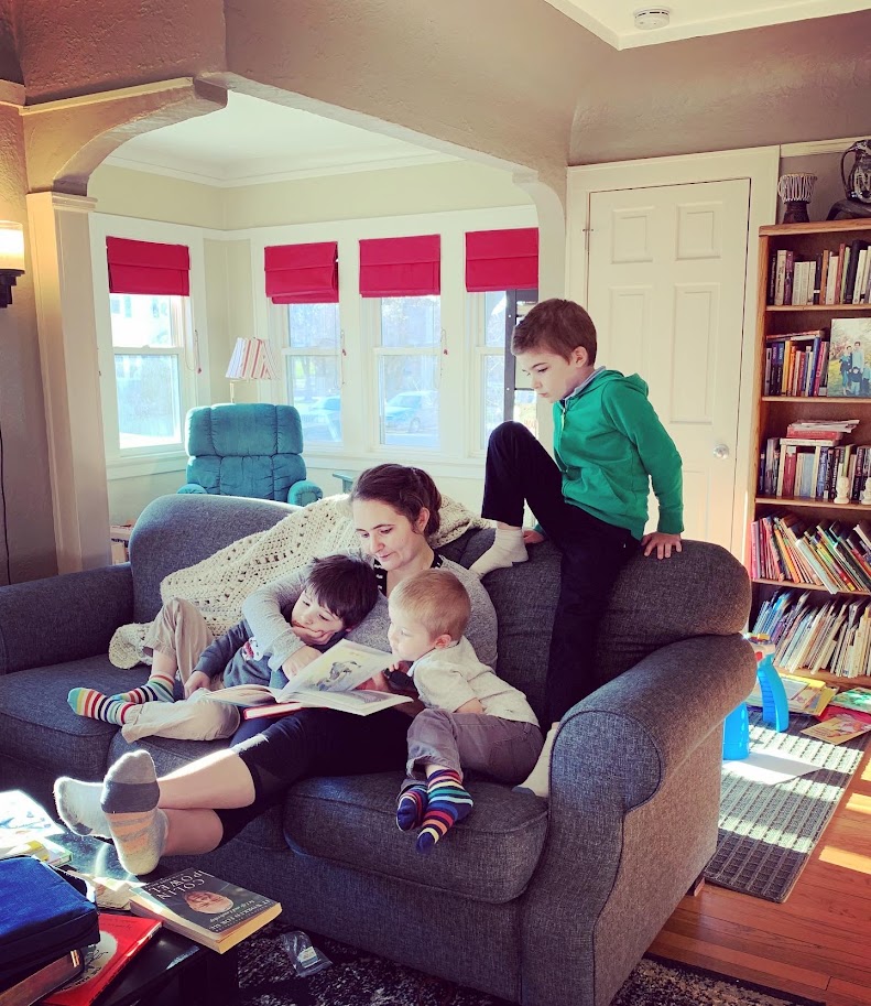 homeschool mom sitting on couch reading to young boys