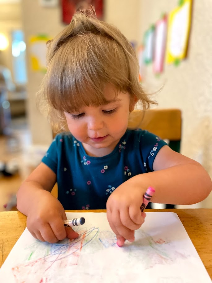 toddler girl scribbling with crayons