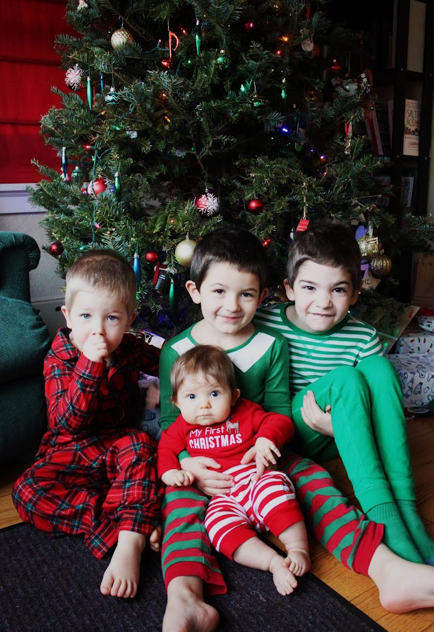 four homeschool children sitting next to christmas tree