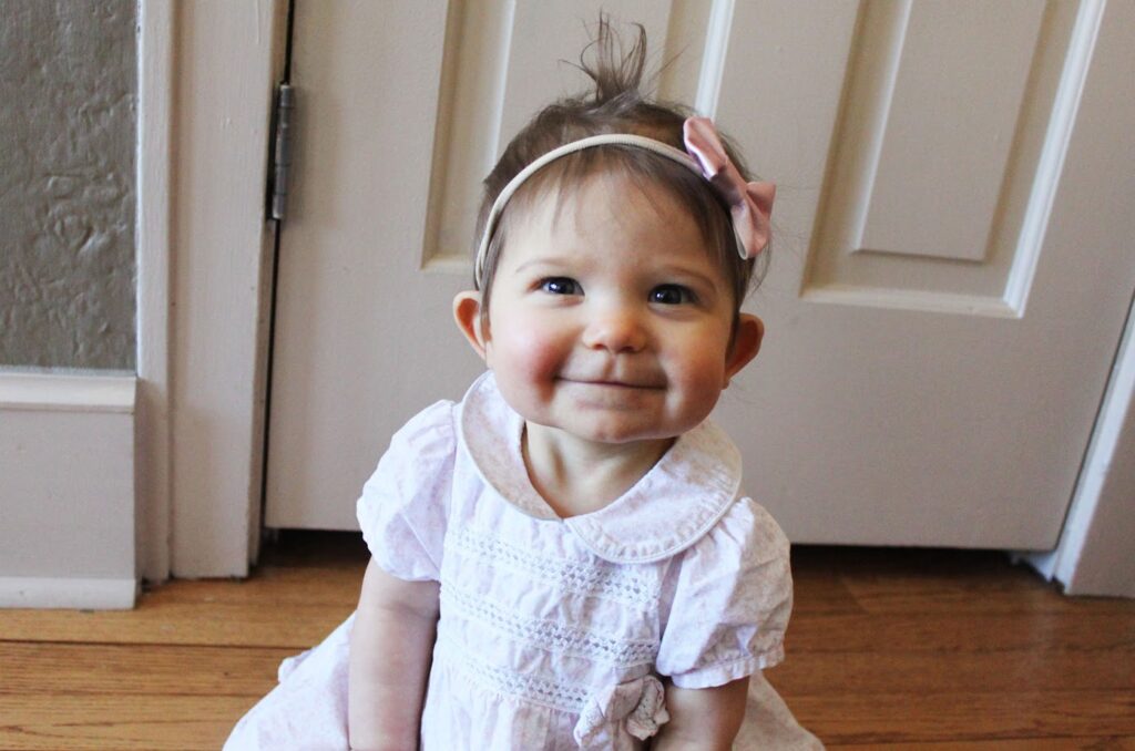 baby girl sitting on the floor wearing pink dress