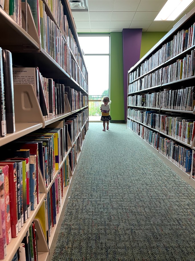 toddler girl walking through the library