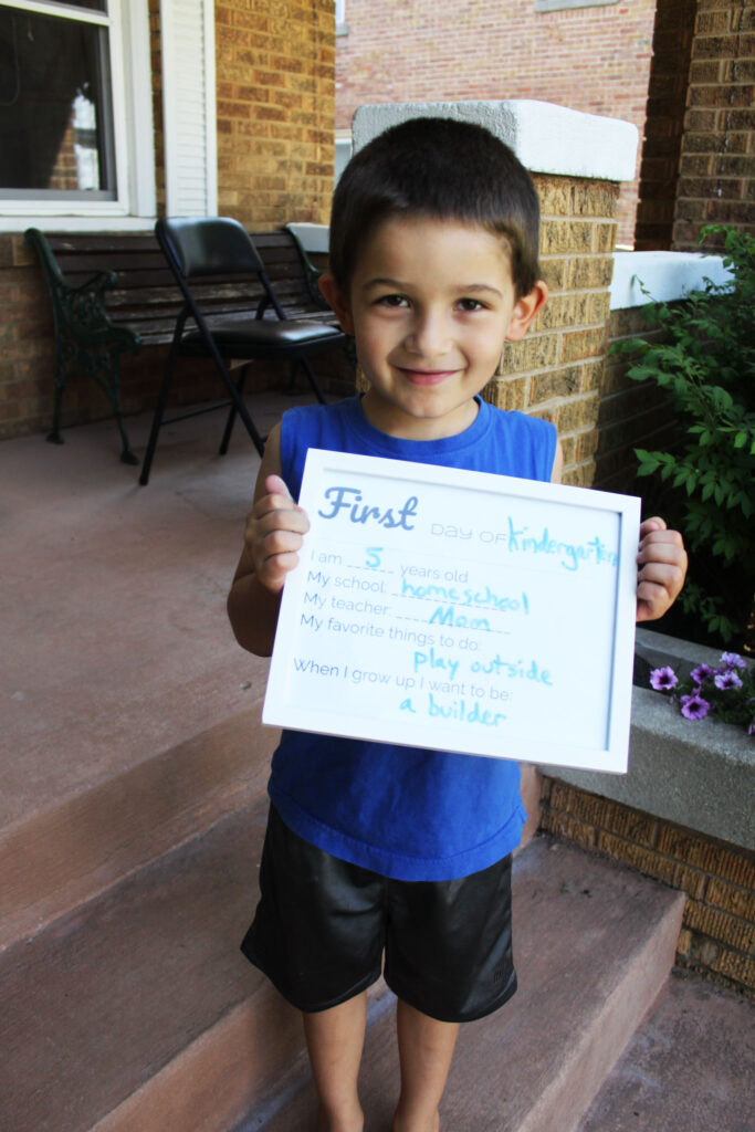 young boy in tank top holding back to school sign