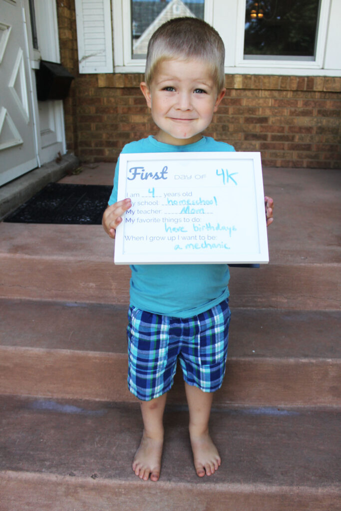 young boy holding back to homeschool sign