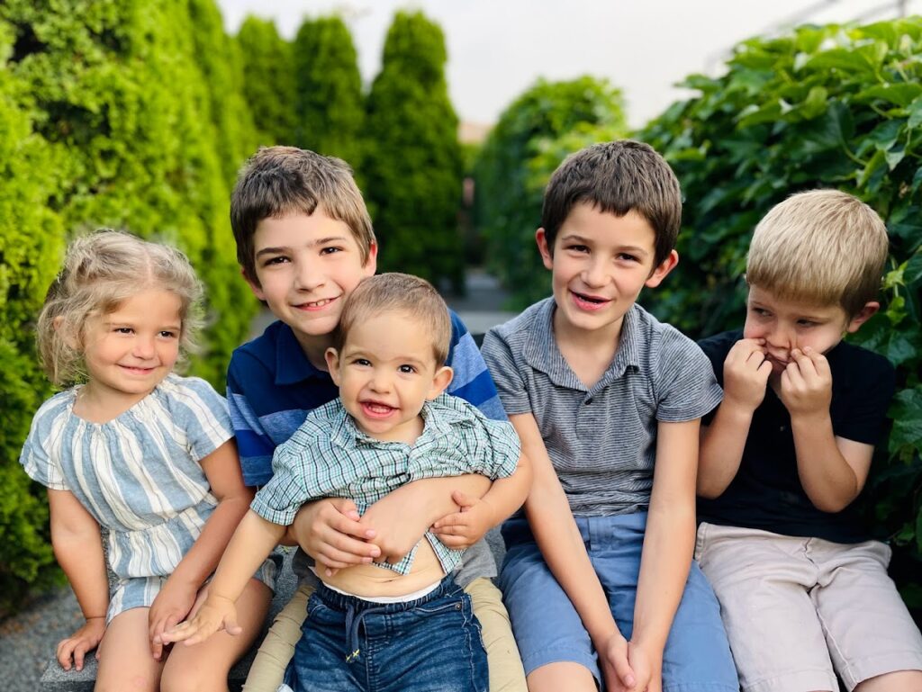 five homeschool kids sitting outside on a bench