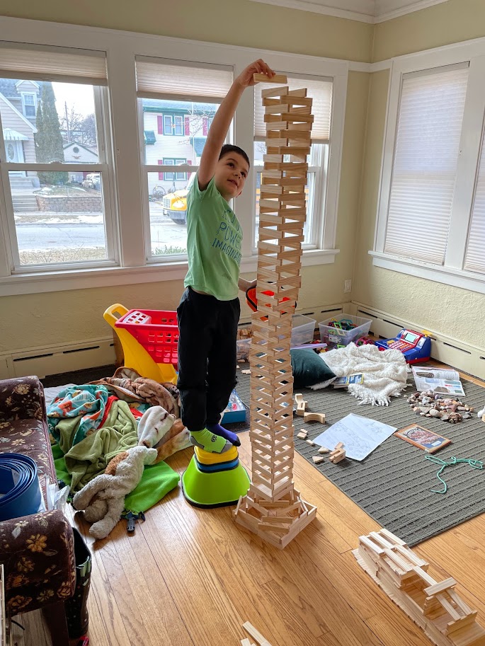 young boy stacking blocks to reach his goals