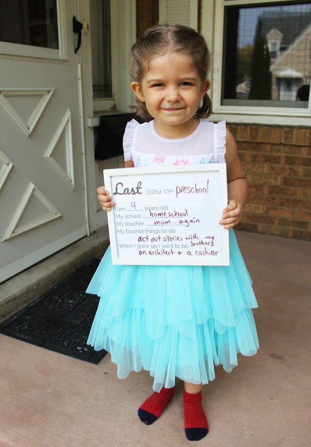 toddler girl holding last day of homeschool sign