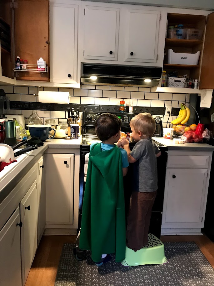 two young boys cooking in kitchen