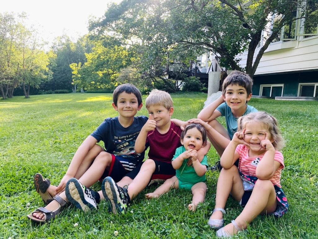 five homeschool children sitting on the grass