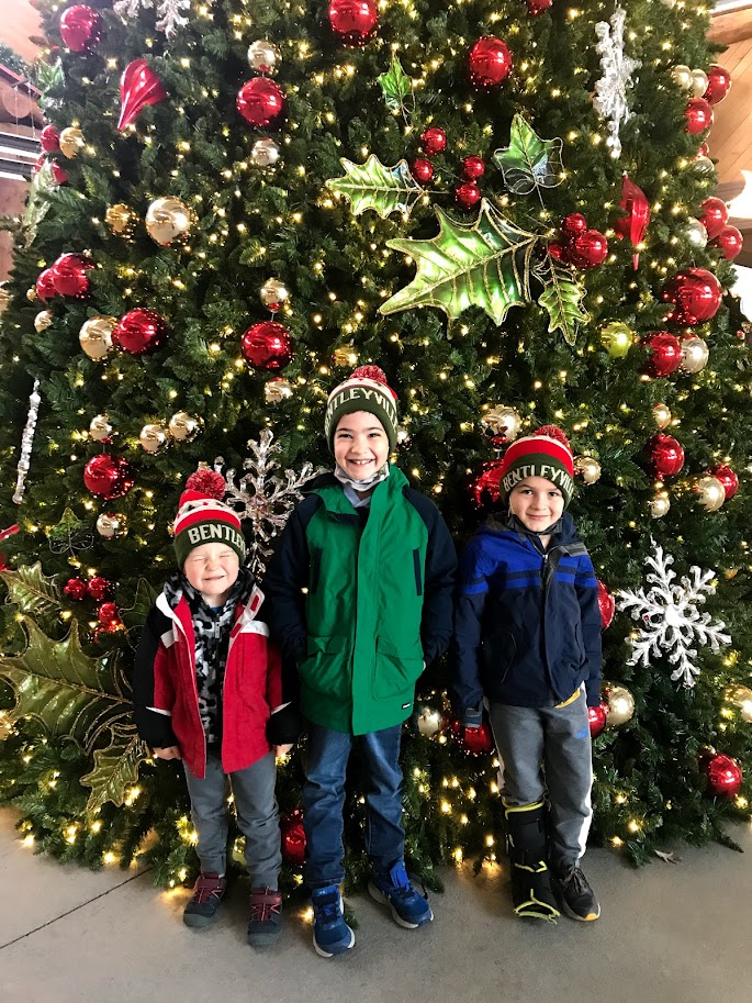 three homeschool boys standing by christmas tree