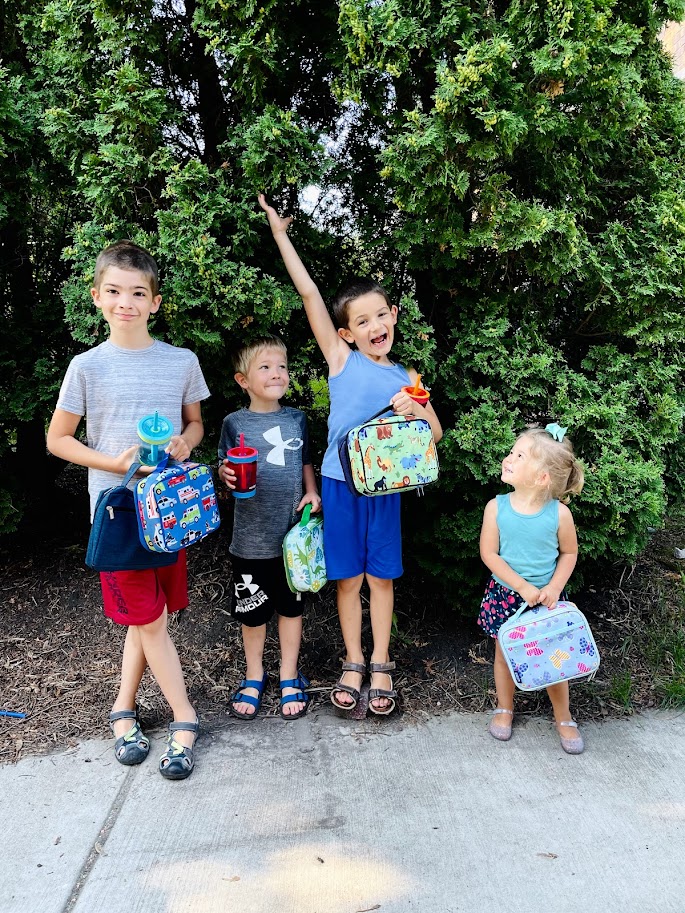 four homeschool kids outside by bushes