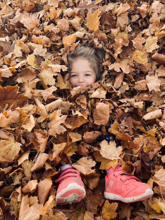 young girl buried in leaf pile