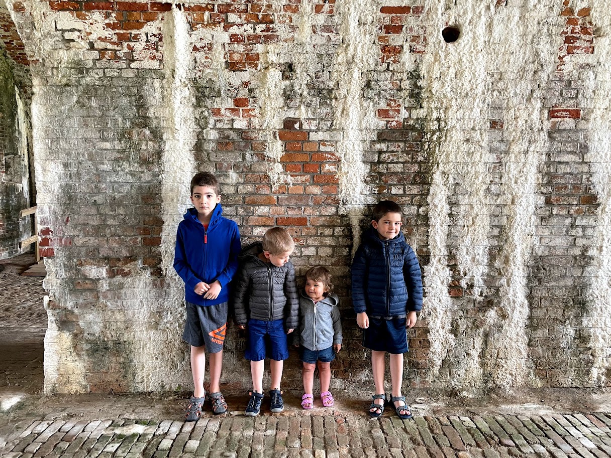 four homeschool children standing by brick wall