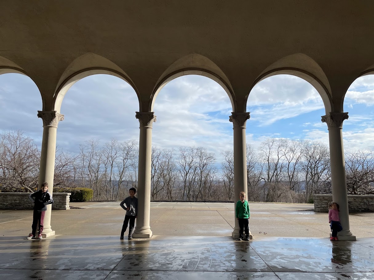 four homeschool children standing by pillars of a building