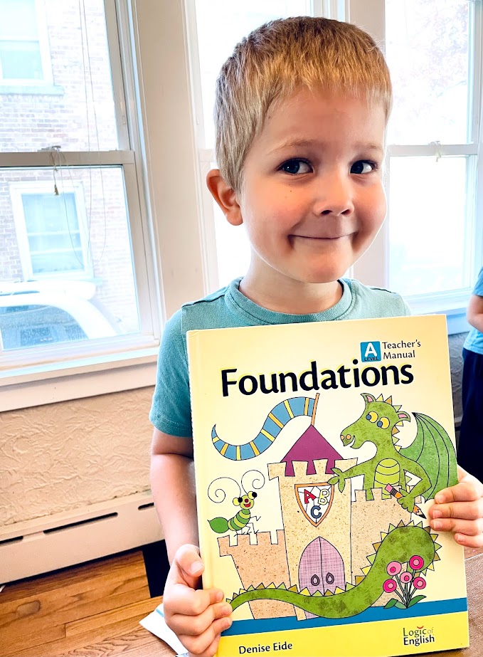 young boy holding phonics curriculum