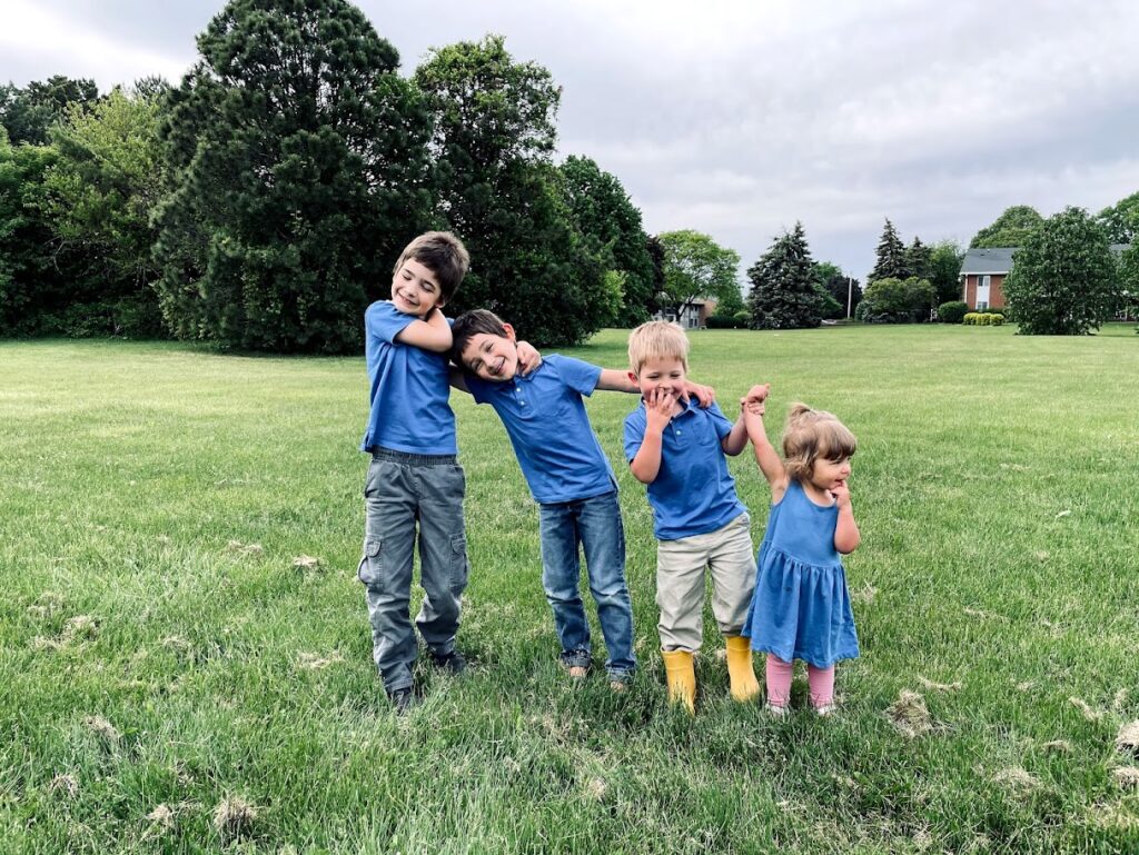 four homeschool kids in a green field