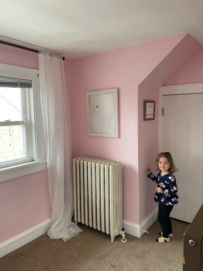 toddler girl in pink bedroom with white curtains