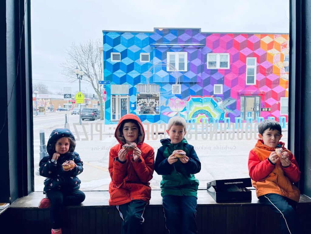 four homeschool children eating donuts