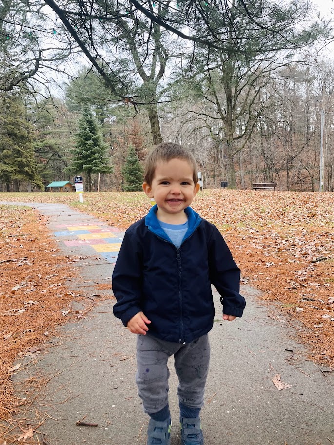 toddler boy walking down a path at home