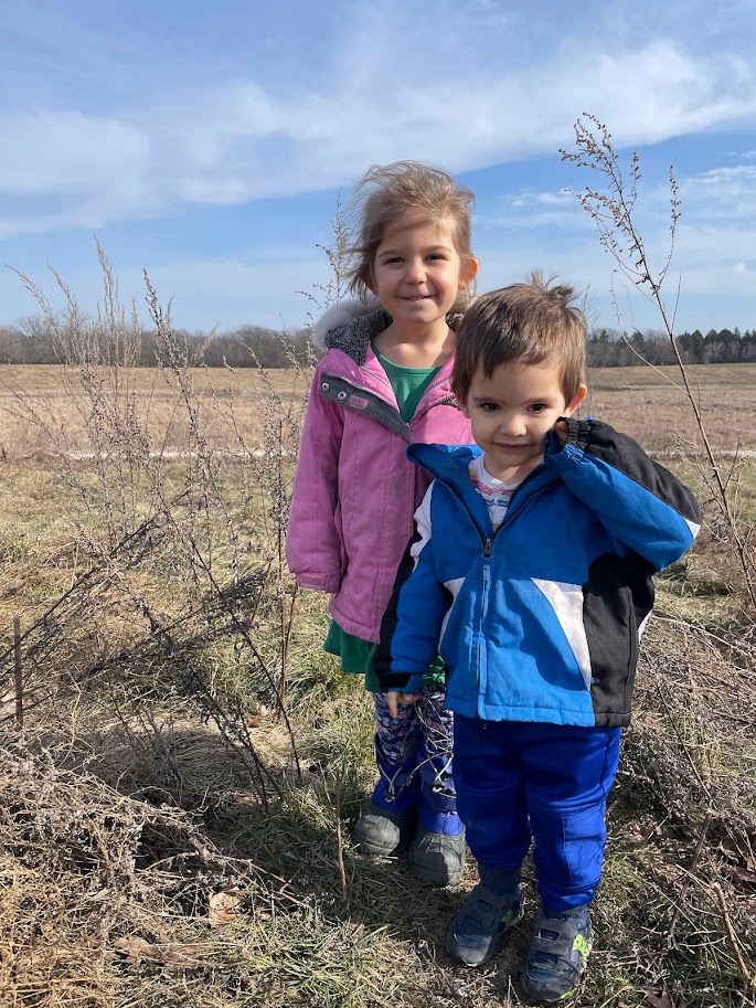 young homeschool girl and toddler boy outside in a field