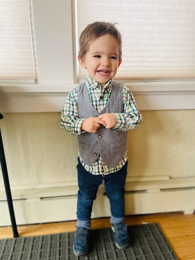 toddler boy standing by window and smiling