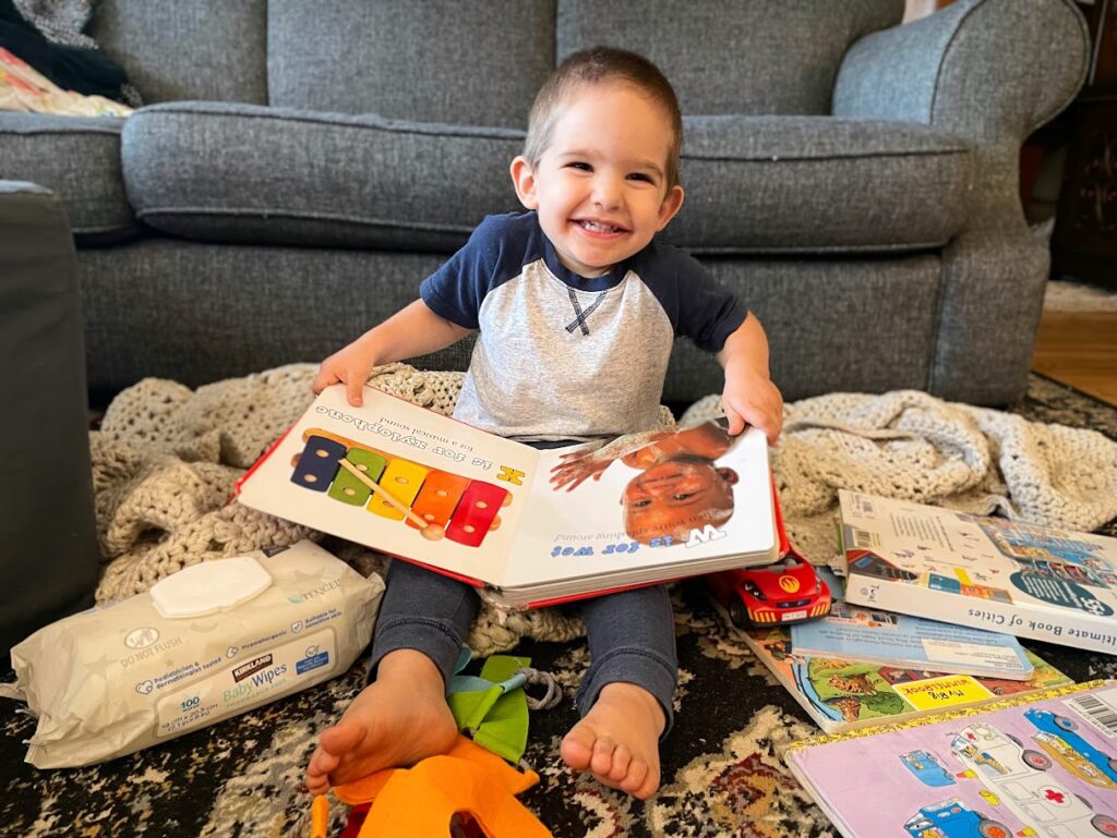 toddler boy reading books on the floor