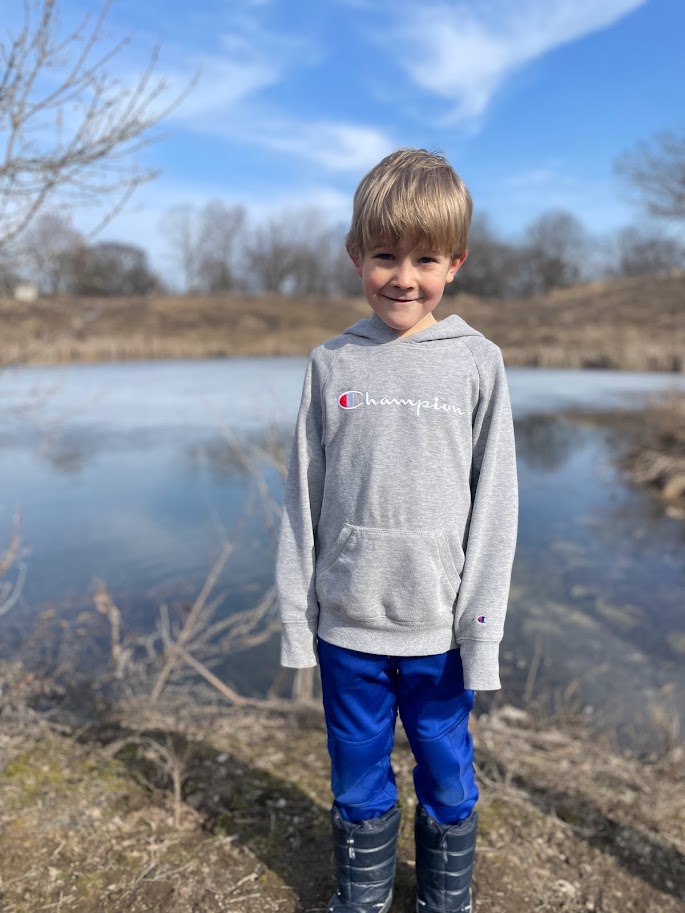 homeschool boy standing outside near a pond