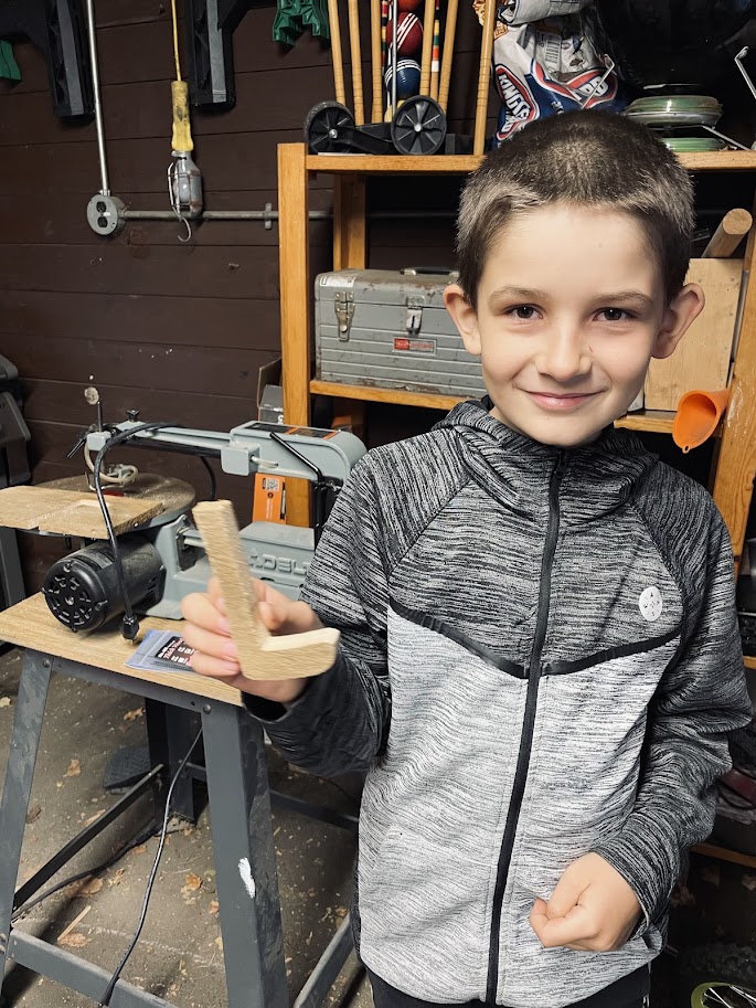 homeschool boy holding a scroll saw creation