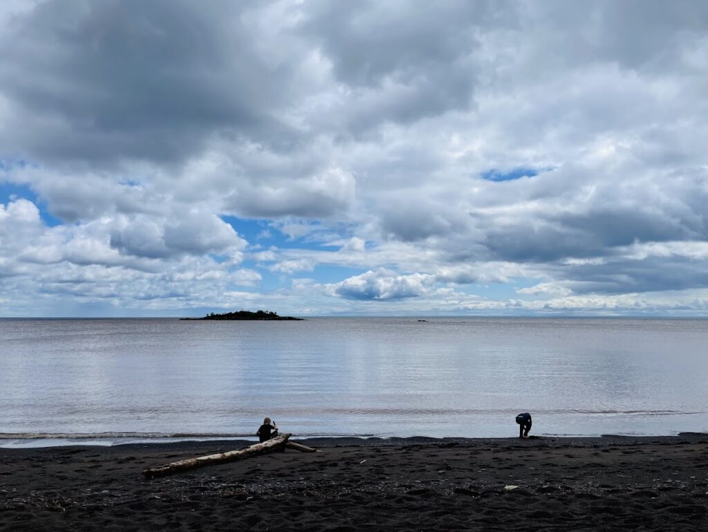 two homeschool boys playing on the shore of lake superior