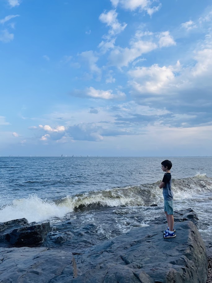 homeschool boy standing on rocks near lake superior