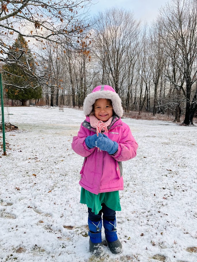 homeschool girl holding candy canes standing in the snow