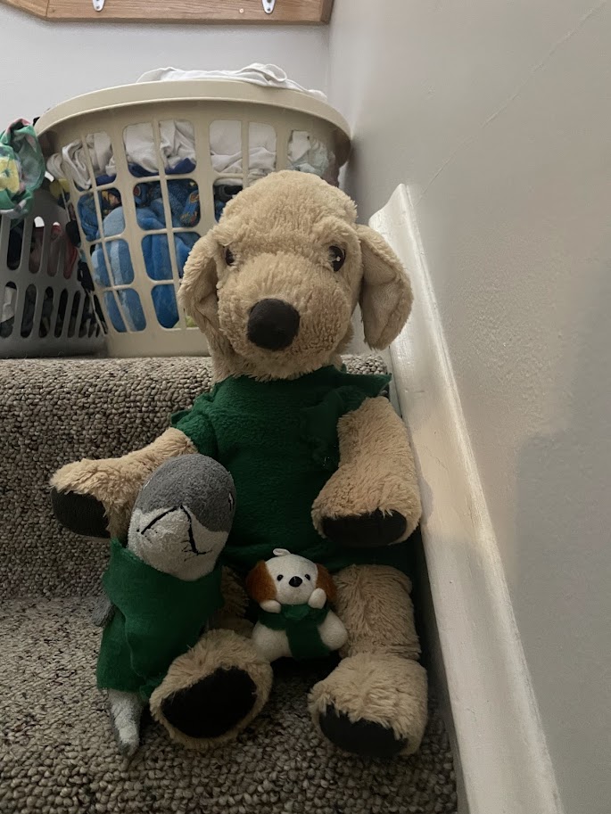 three stuffed animals wearing handmade clothes sitting on the steps