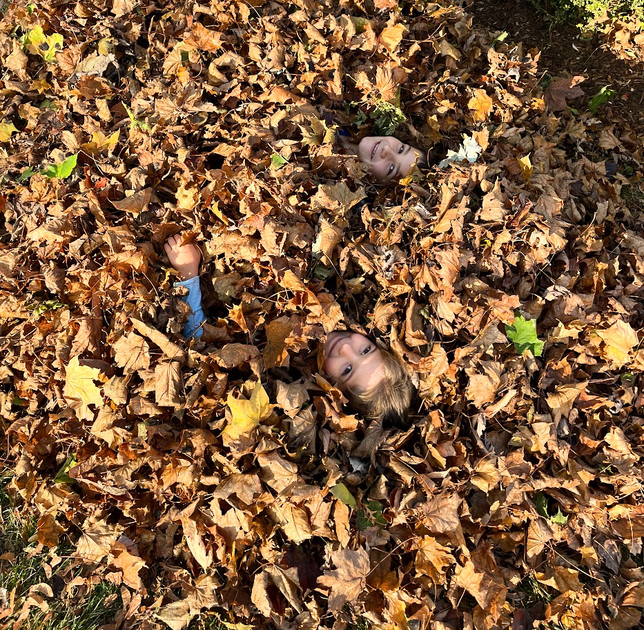 homeschool boy and girl buried in a pile of leaves