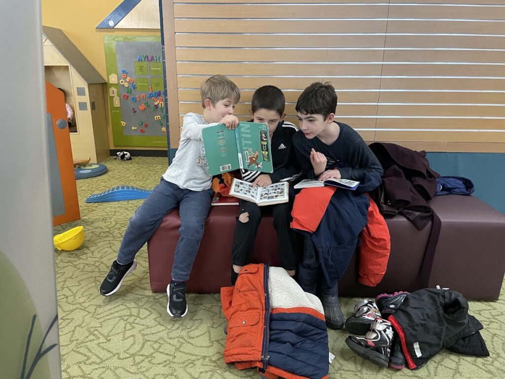 three homeschool boys reading a book together at the library