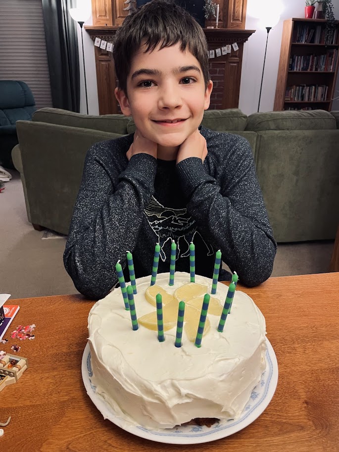 homeschool boy sitting at a table with a birthday cake and candles