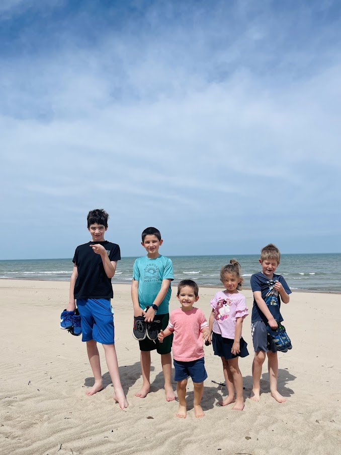 five homeschool children standing at the beach on the shores of Lake Michigan