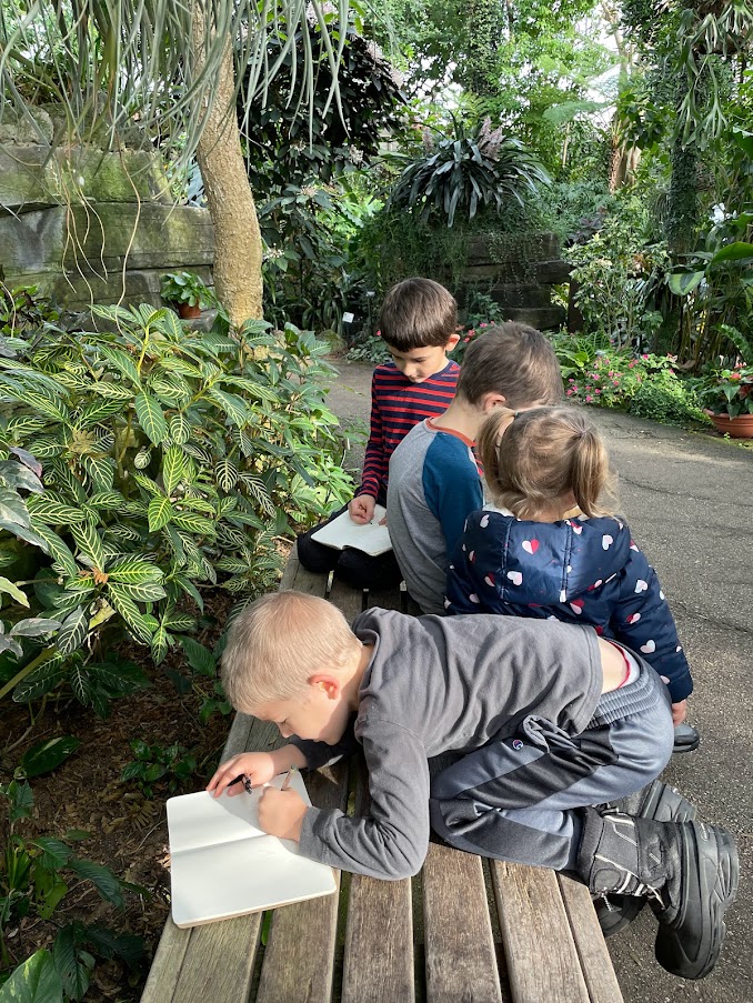 four homeschool children working on nature study at an indoor botanical garden
