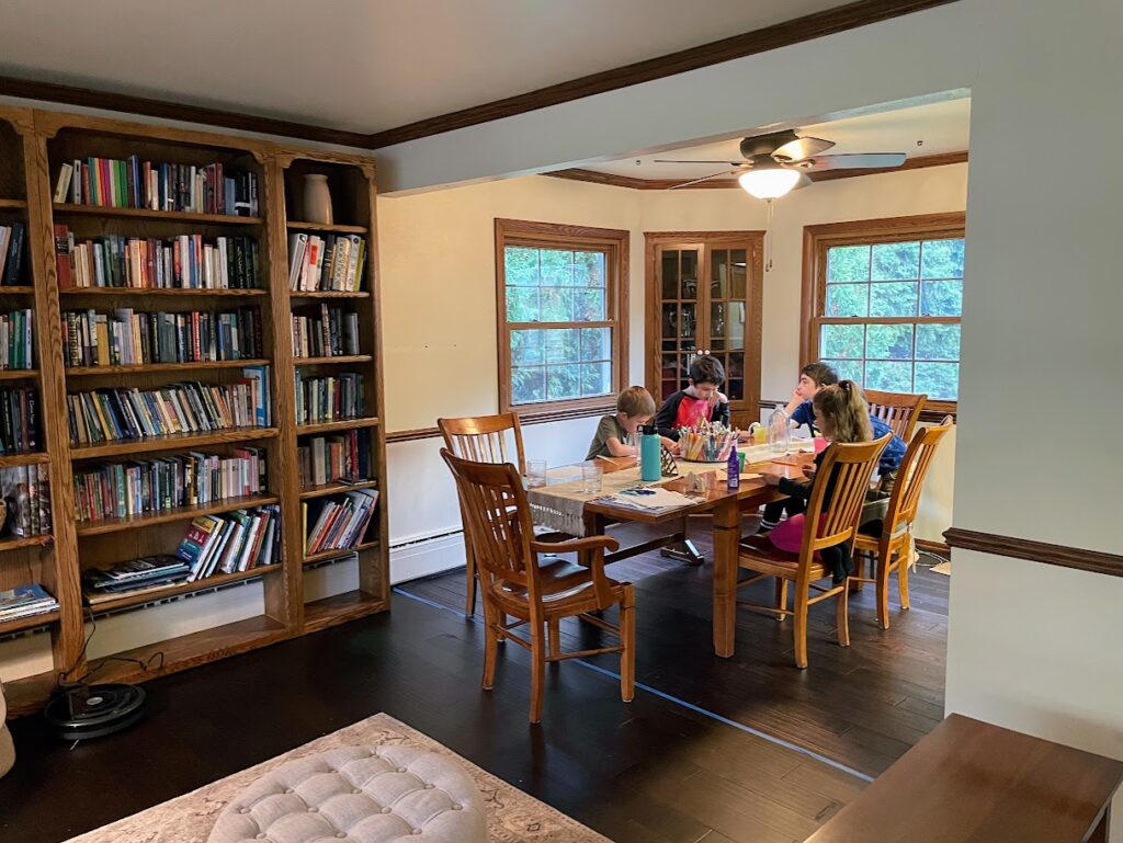 four homeschool kids sitting around the dining room table and working on school work