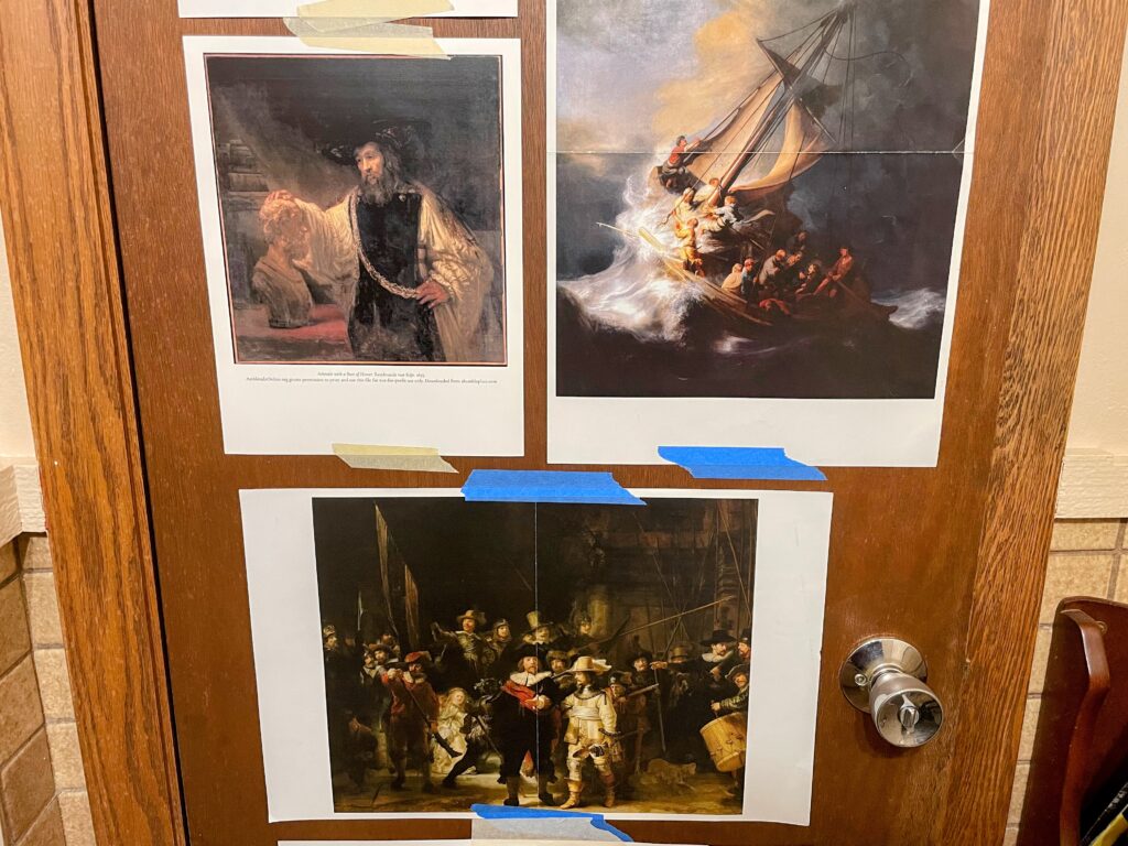three prints of Rembrandt paintings taped to the back of a door