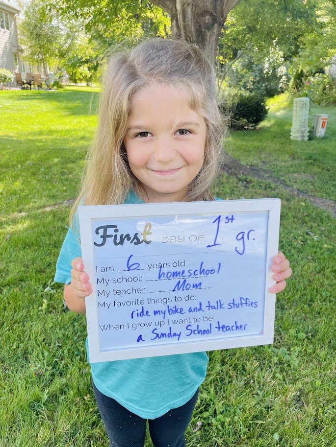homeschooled first grade girl holding a first day of school sign