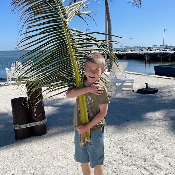 homeschool boy holding a large palm tree branch