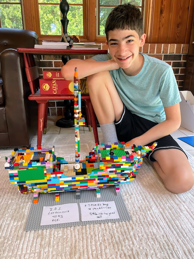 homeschool teen boy with a large ship made of legos